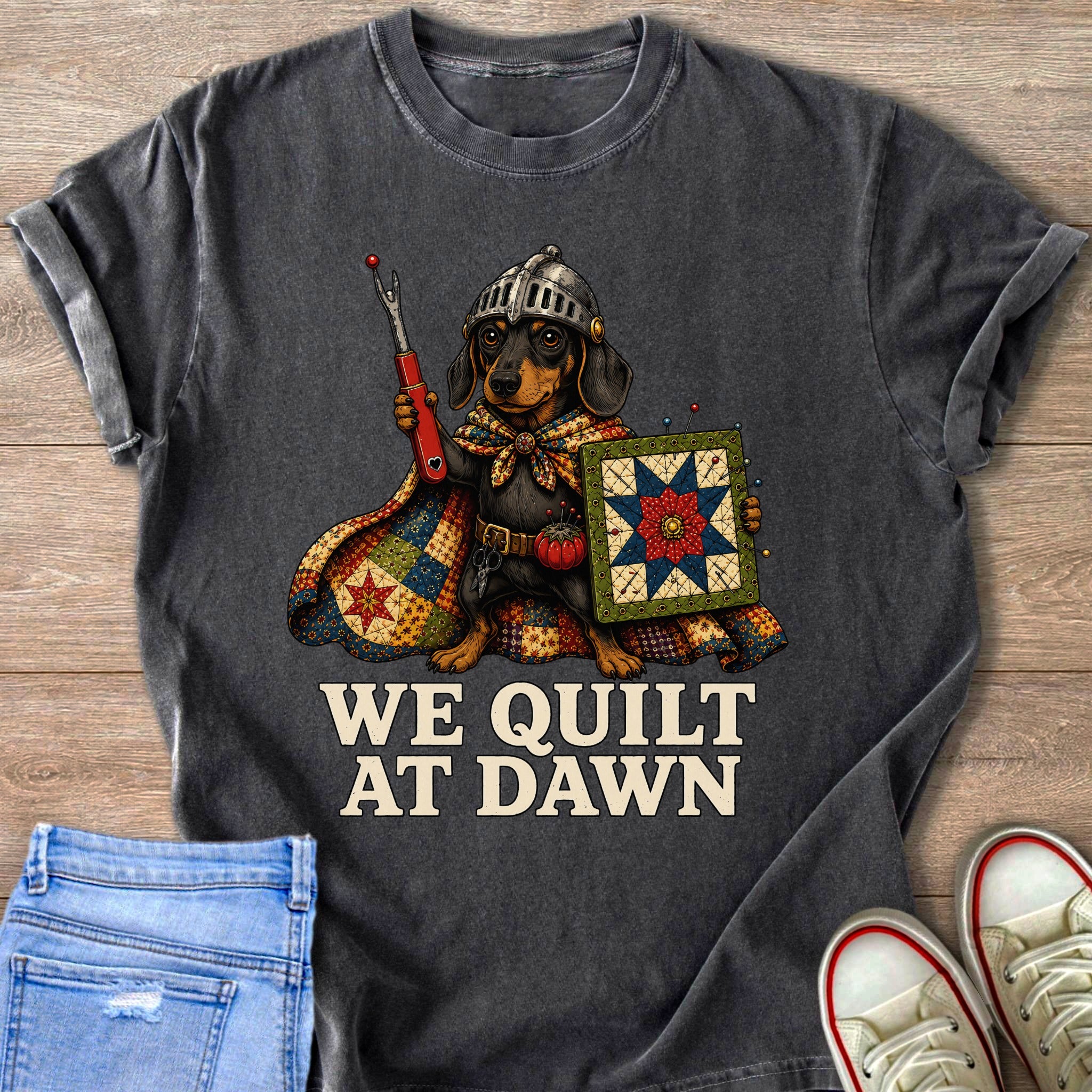 Dachshund wearing a helmet holding a seam ripper and quilt, text reads "WE QUILT AT DAWN".