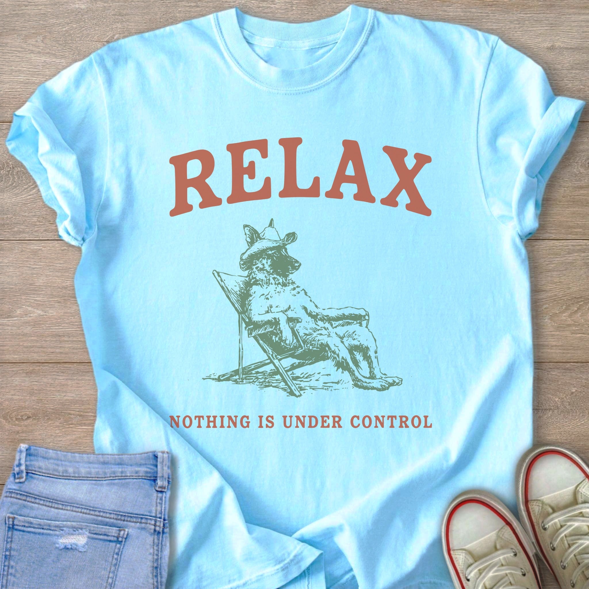 Light blue t-shirt with "RELAX" above a dog wearing a hat sitting in a chair.