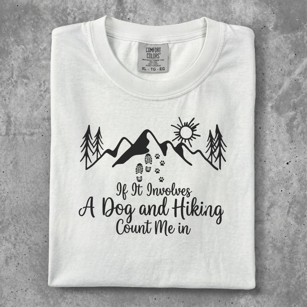 White t-shirt with "If It Involves A Dog and Hiking Count Me In" graphic.