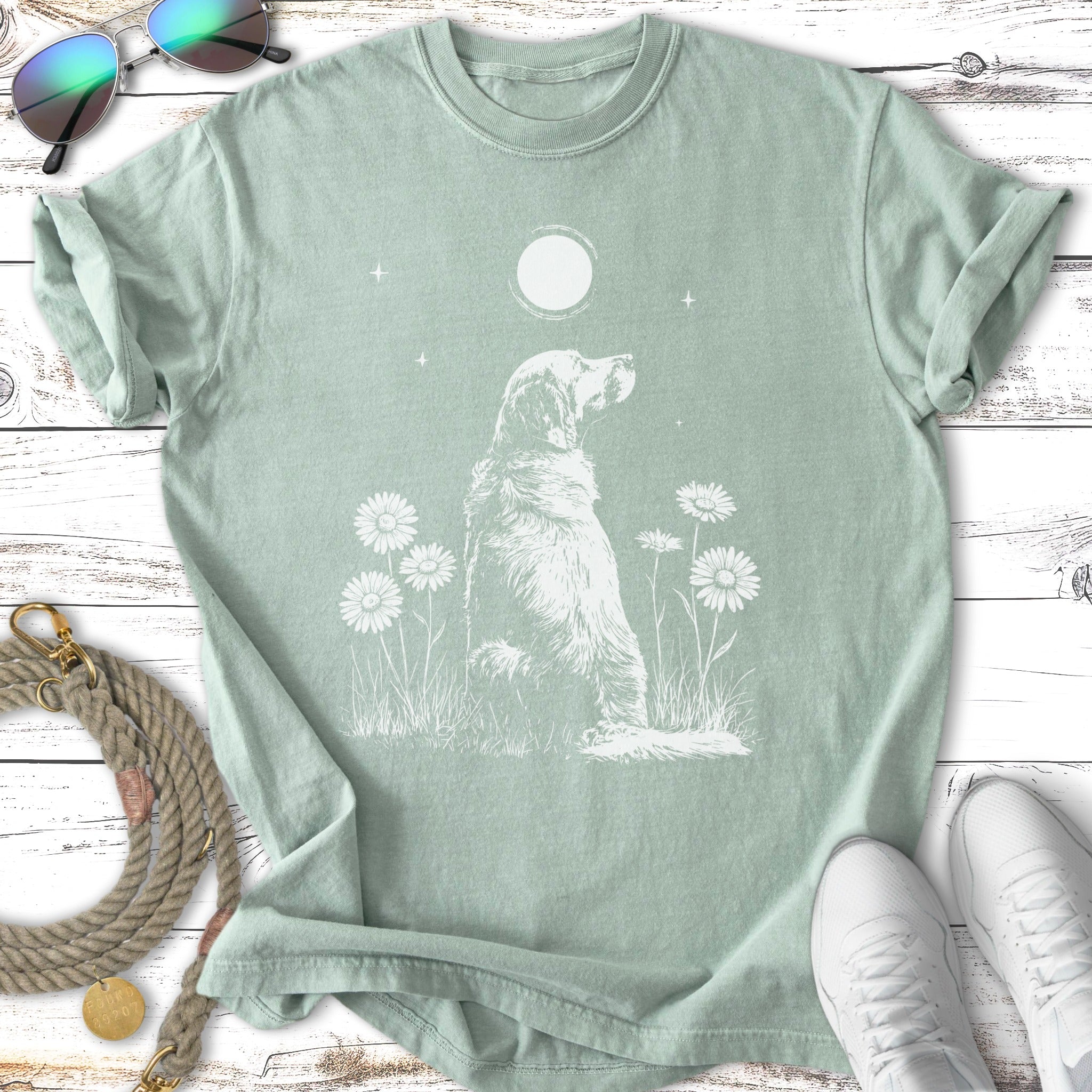 White outline of a dog sitting in grass with daisies under a moon.