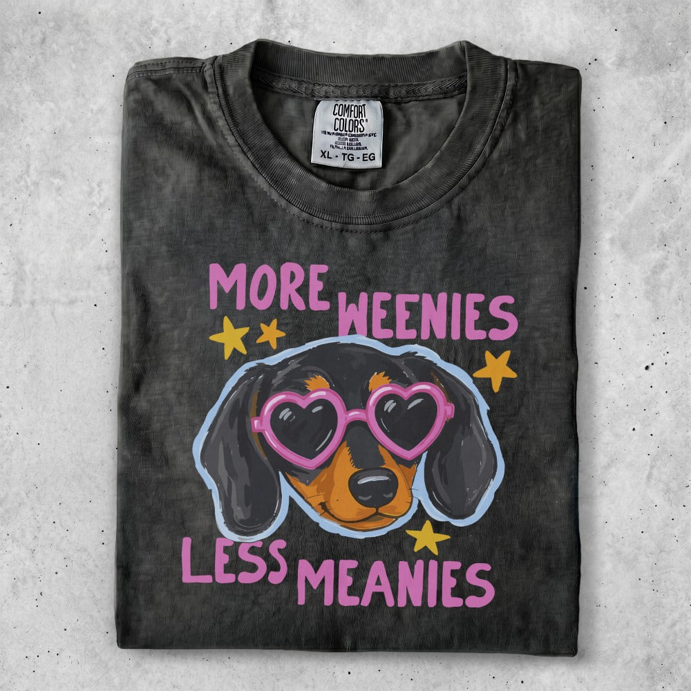 Dark t-shirt with a dachshund wearing pink heart sunglasses and text "More Weenies Less Meanies".
