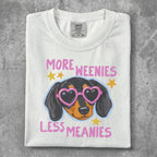 White t-shirt with a cartoon dachshund wearing heart-shaped glasses, saying "More weenies, less meanies."