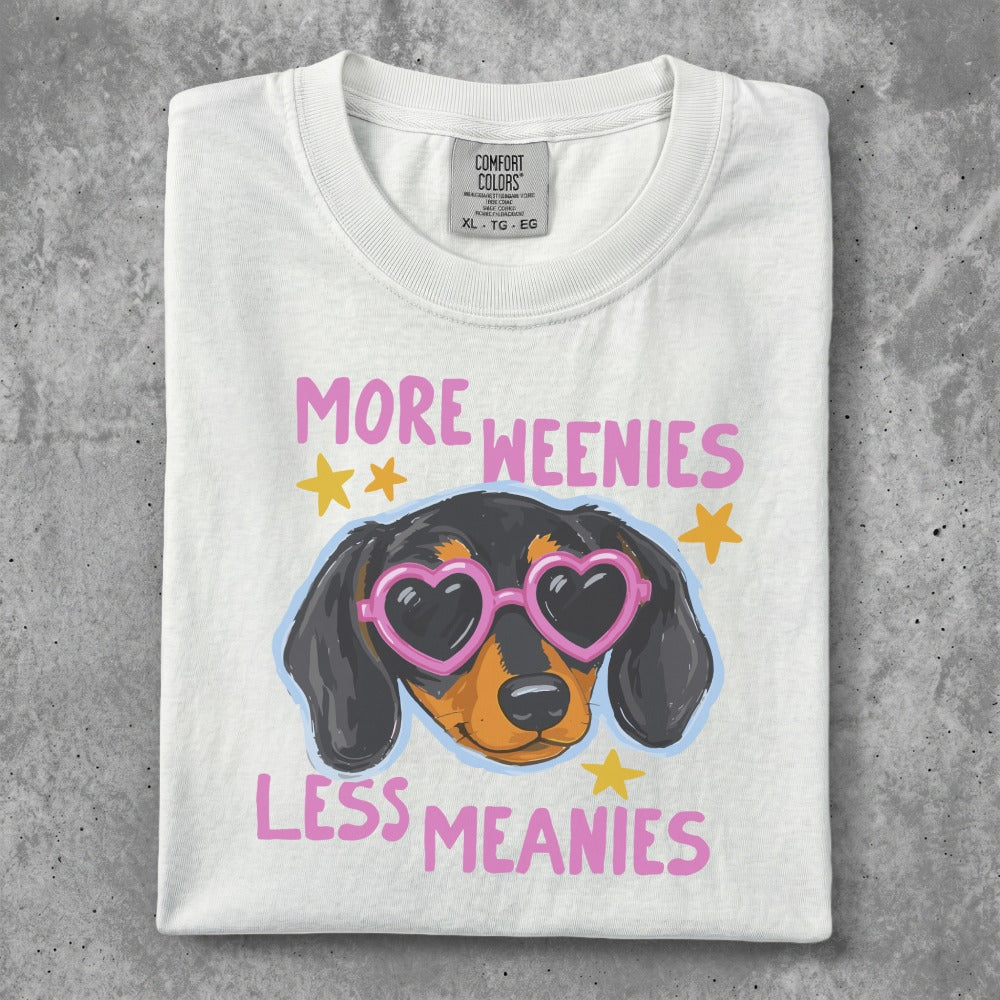 White t-shirt with a cartoon dachshund wearing heart-shaped glasses, saying "More weenies, less meanies."