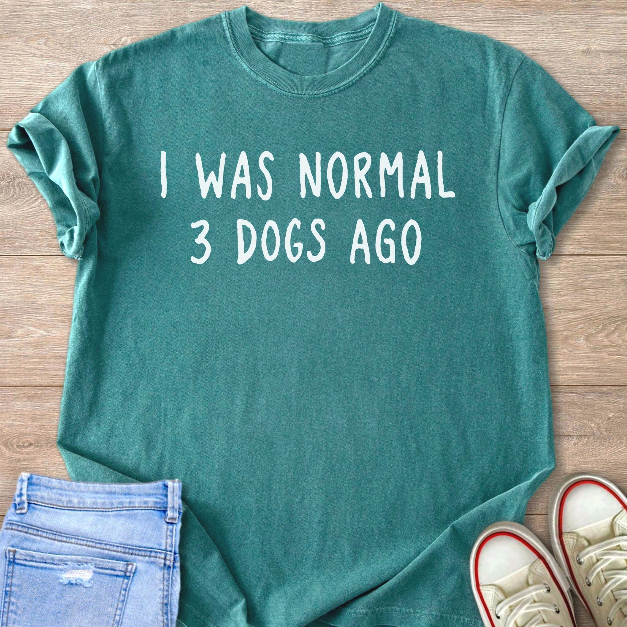 Teal t-shirt with "I WAS NORMAL 3 DOGS AGO" text printed in white.