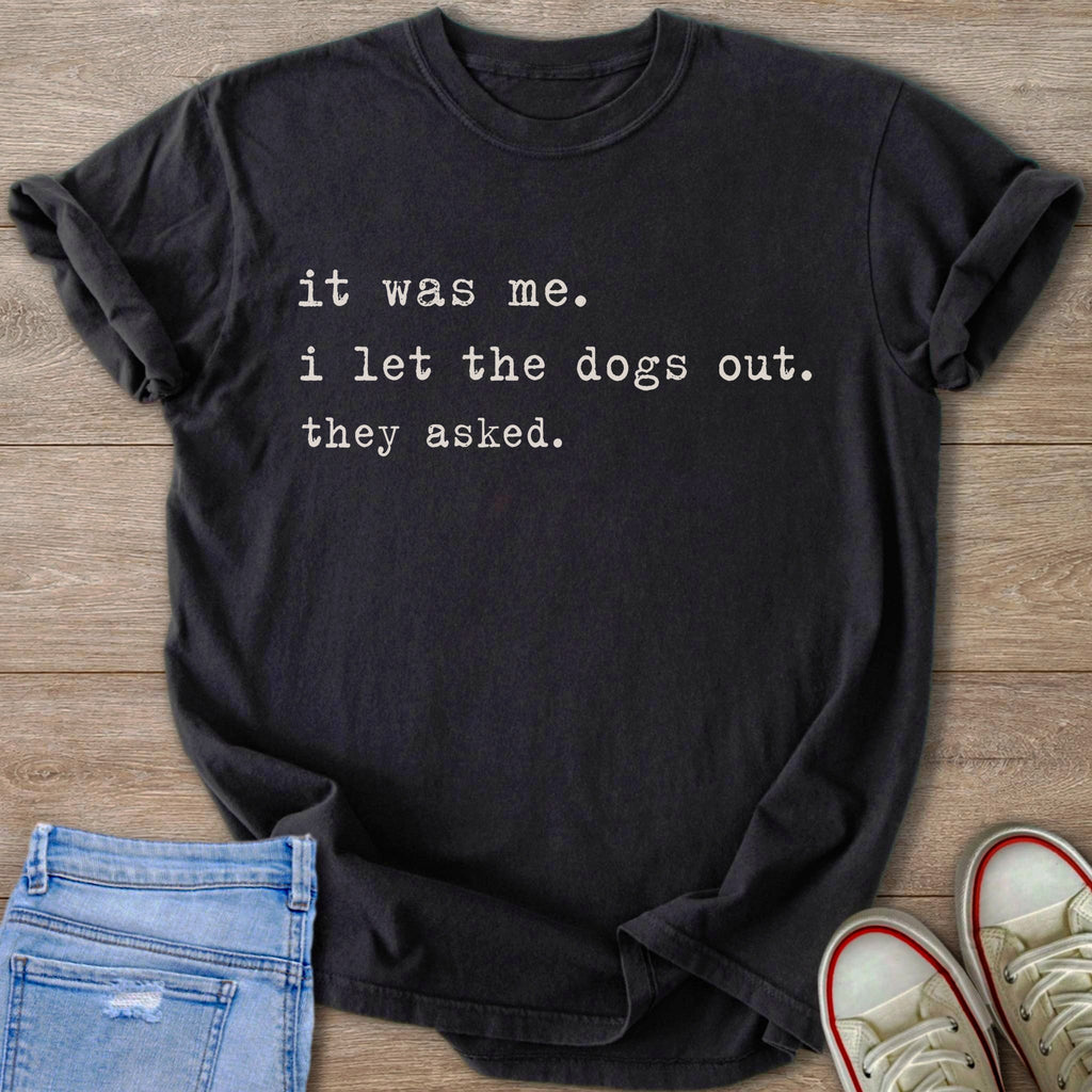 Black t-shirt with white text "it was me. i let the dogs out. they asked."