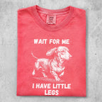 Coral Comfort Colors t-shirt with "WAIT FOR ME I HAVE LITTLE LEGS" and dachshund graphic.