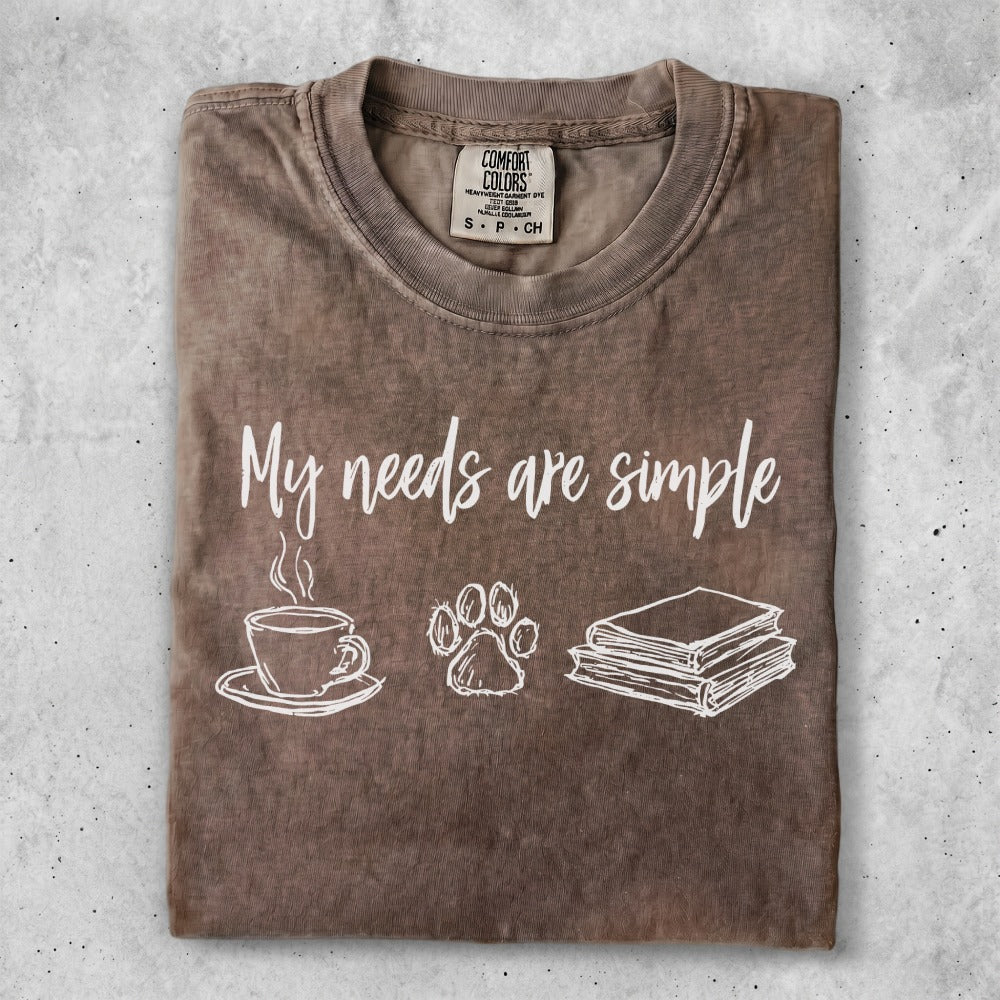 Brown t-shirt with "My needs are simple" text, coffee cup, paw print, and books.