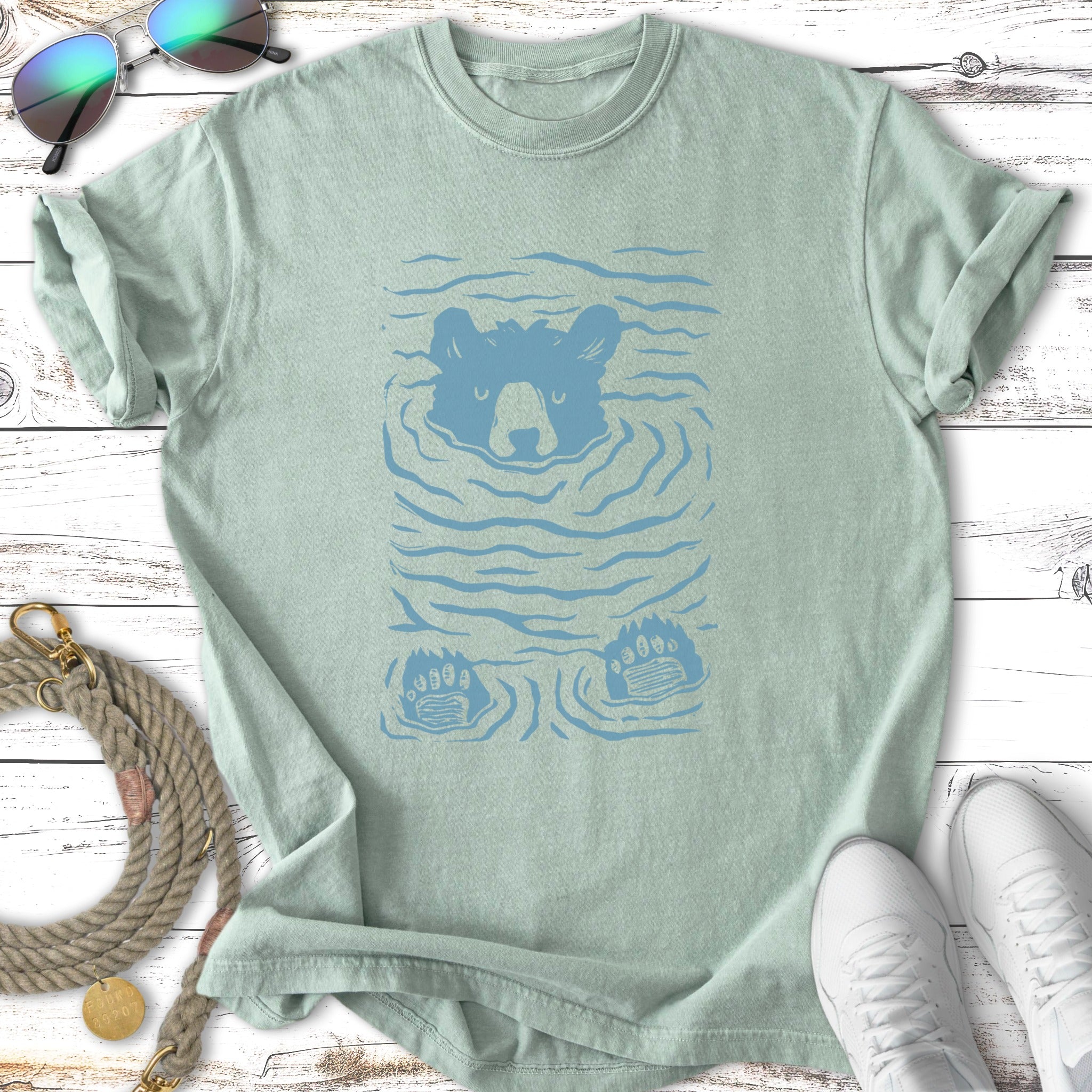 Blue bear submerged in water with paws visible, on a light green t-shirt.