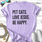 Purple t-shirt with "PET CATS. LOVE JESUS. BE HAPPY." text.