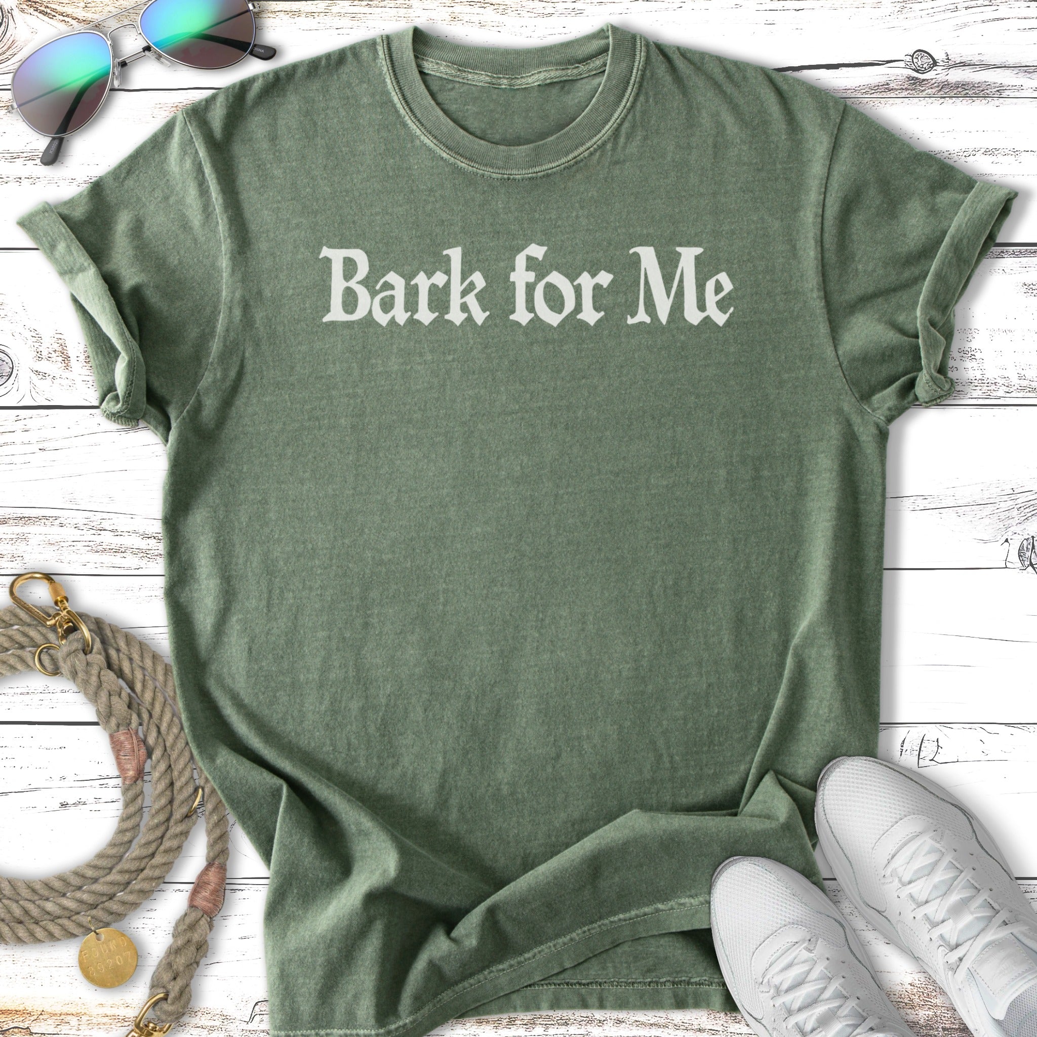 Green t-shirt with "Bark for Me" text and casual accessories.