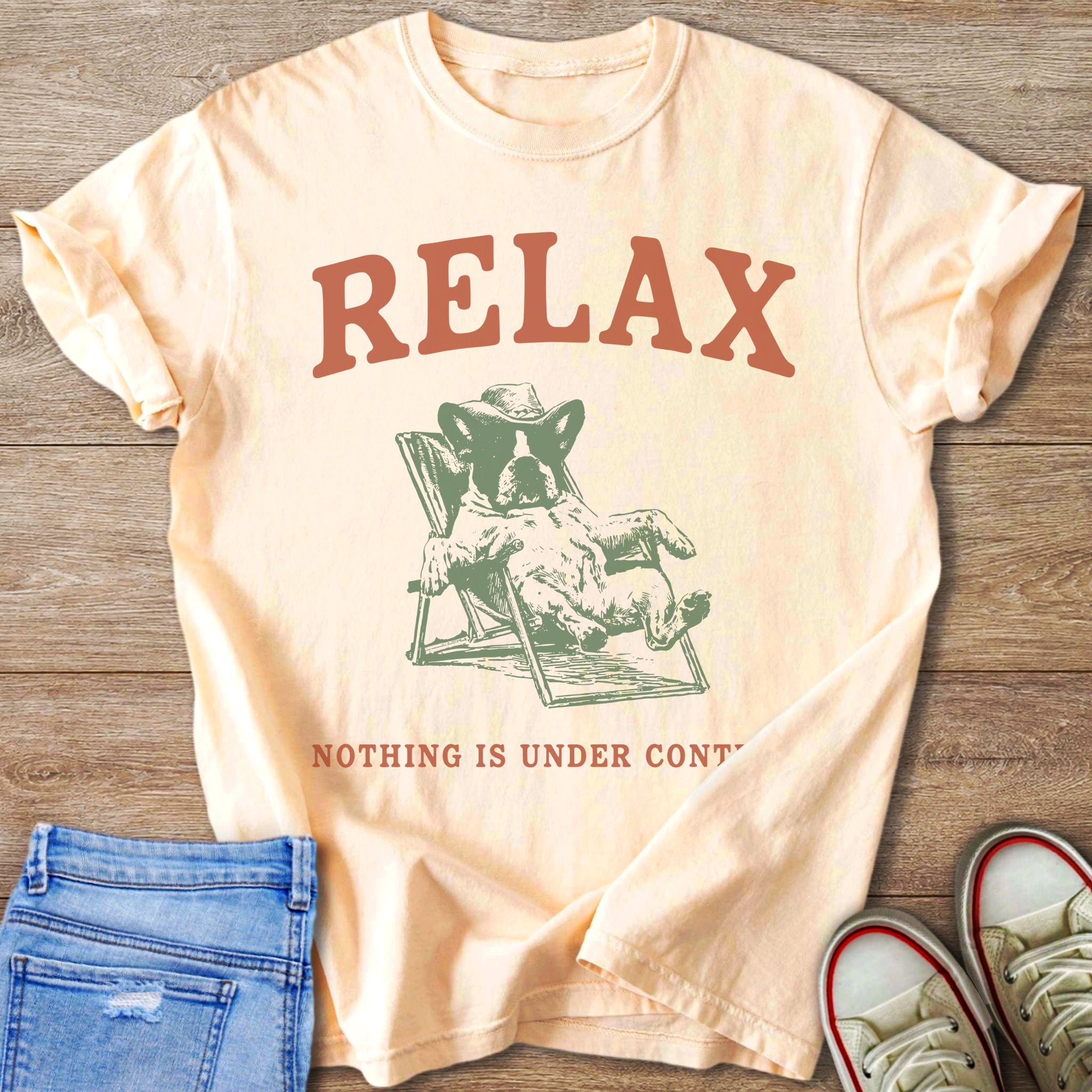 Peach t-shirt with "RELAX" and a dog in a lounge chair and "NOTHING IS UNDER CONT".