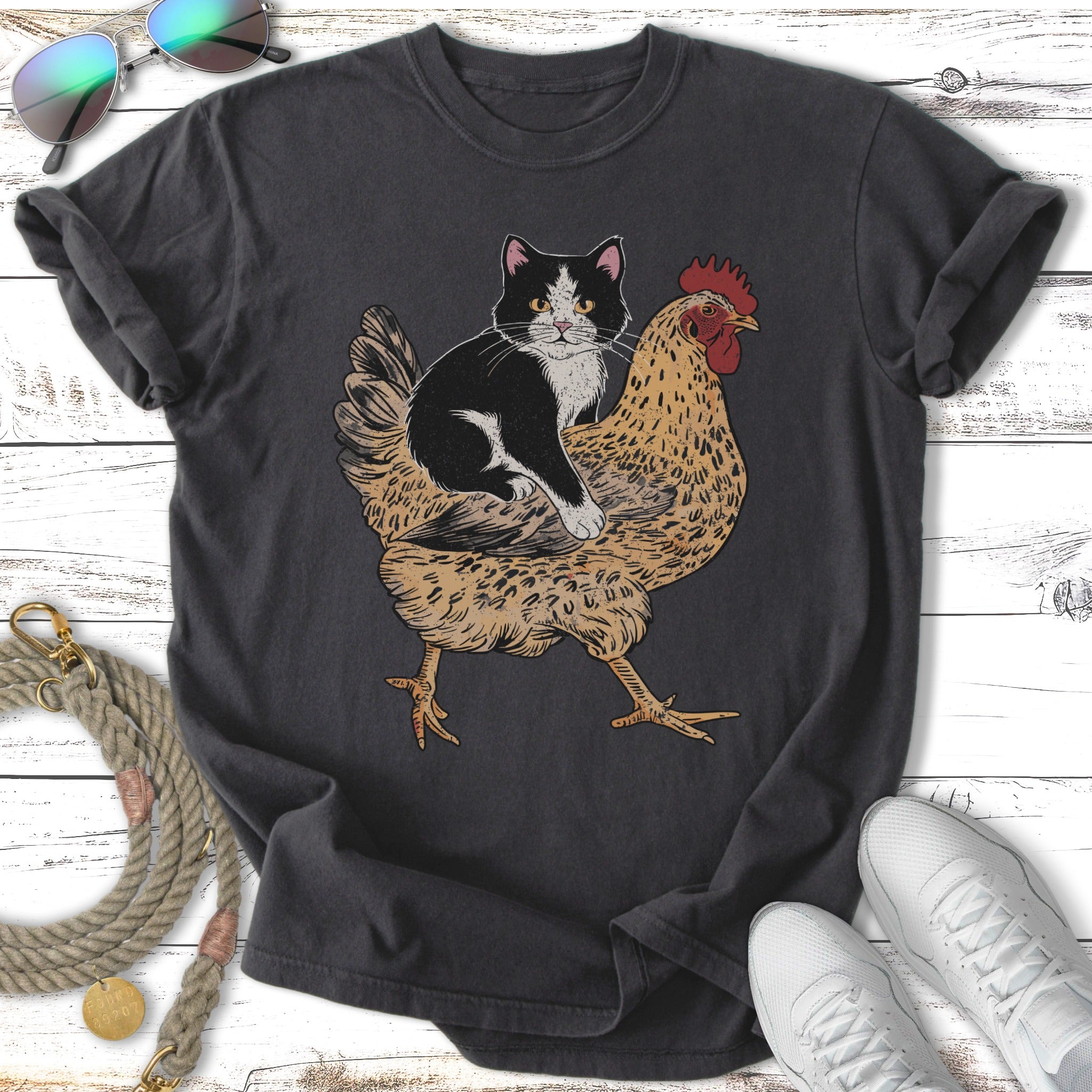 Black and white cat riding a chicken on a dark t-shirt.