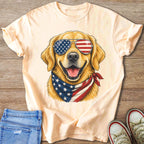 Golden retriever wearing American flag sunglasses and bandana on light peach t-shirt.
