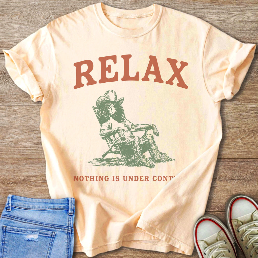 Peach t-shirt with "RELAX NOTHING IS UNDER CONT" and a dog in a cowboy hat relaxing.