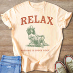 Peach t-shirt with "RELAX NOTHING IS UNDER CONT" and a dog in a cowboy hat relaxing.