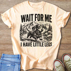 Peach t-shirt with black graphic of a dachshund running through mountains, text "WAIT FOR ME I HAVE LITTLE LEGS".