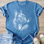 White sketch of French bulldog blowing dandelion seeds on a blue t-shirt.