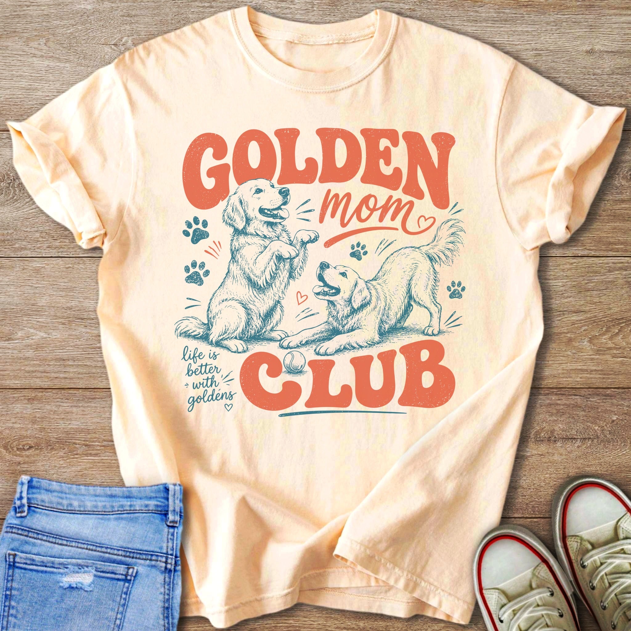 Light peach t-shirt with a distressed graphic of two golden retrievers, "Golden Mom Club," and "life is better with goldens."