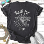 Dark for me wolf graphic t-shirt on a wooden surface.