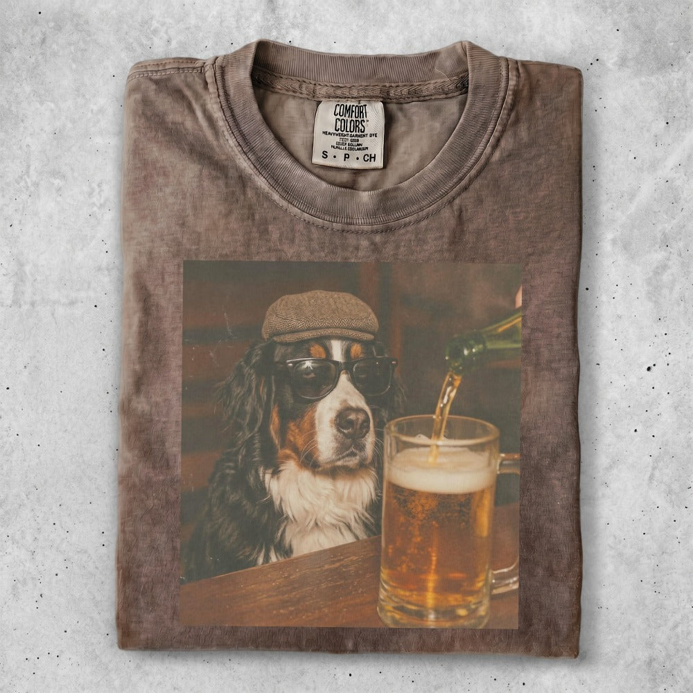 Bernese Mountain Dog wearing sunglasses and a hat, sitting by a beer.