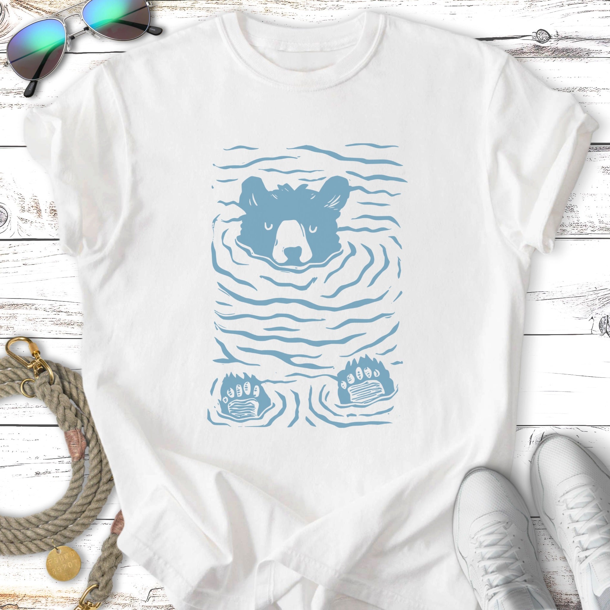 Blue bear swimming with paws visible, on a white t-shirt.