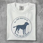 White t-shirt with a blue circular graphic of a dog and text "ALL FOOD MUST GO TO THE LAB FOR TESTING".