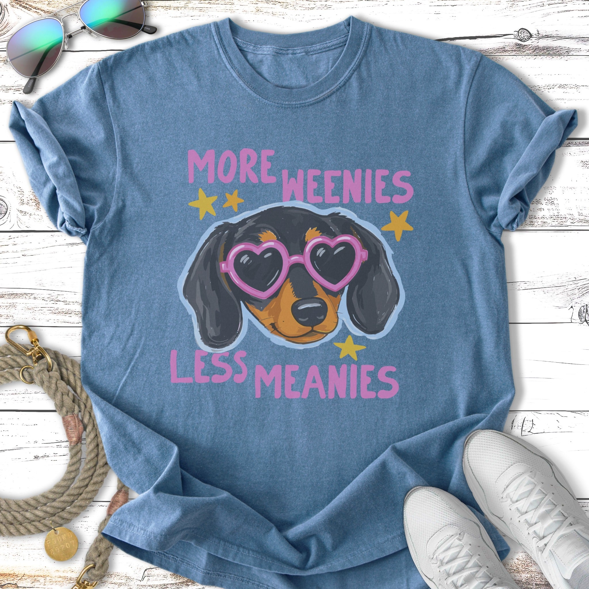 Blue t-shirt with a dachshund wearing heart-shaped sunglasses and text "More Weenies Less Meanies."
