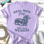 Lilac t-shirt with illustration of a dachshund and text "Real men play with their weiners".