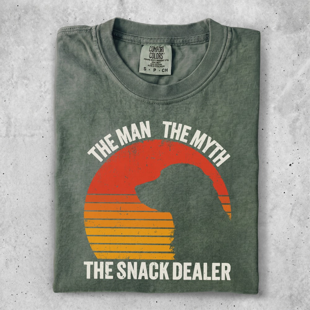 Green t-shirt with "The Man the Myth the Snack Dealer" slogan over a dog silhouette.