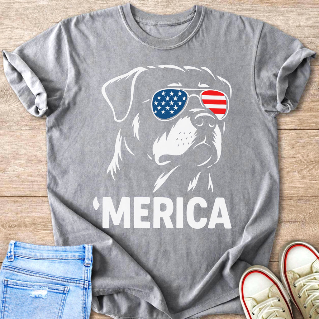 Dog wearing American flag sunglasses with "MERICA" text on t-shirt.