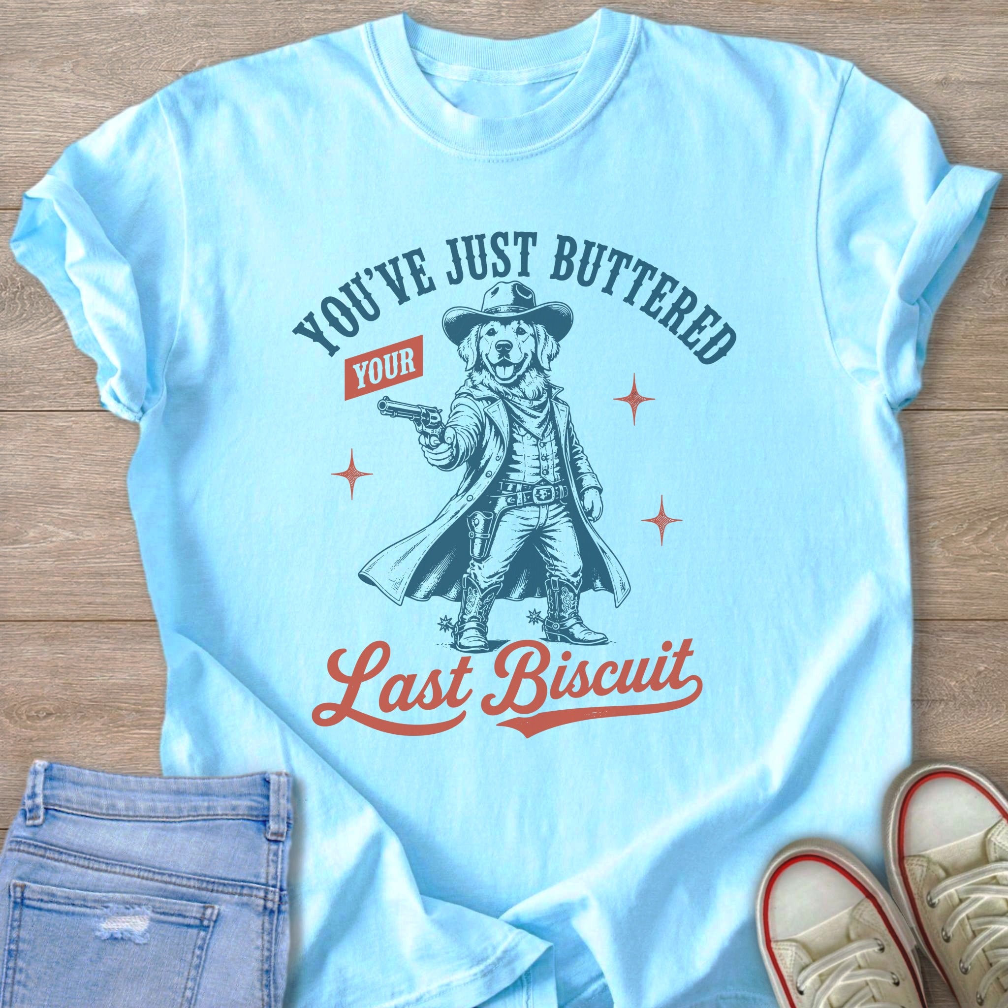 Light blue t-shirt with graphic of a dog in cowboy attire holding a gun.