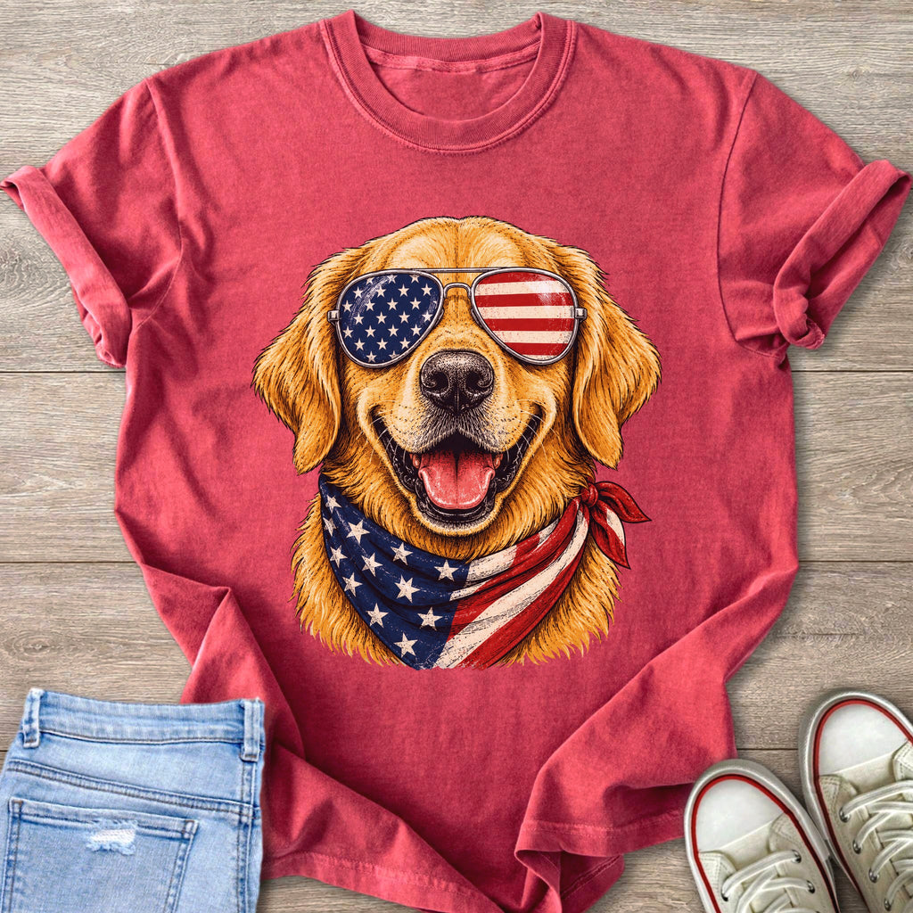 Golden retriever wearing American flag sunglasses and bandana on red t-shirt.