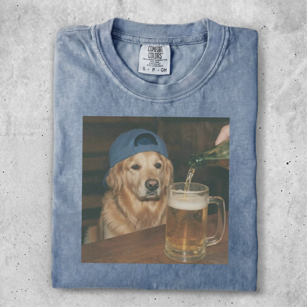 Golden retriever wearing a blue cap being poured beer from a bottle.