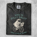 T-shirt with pug riding a bicycle and text "BORN TO DILLY DALLY FORCED TO PICK UP THE PACE."