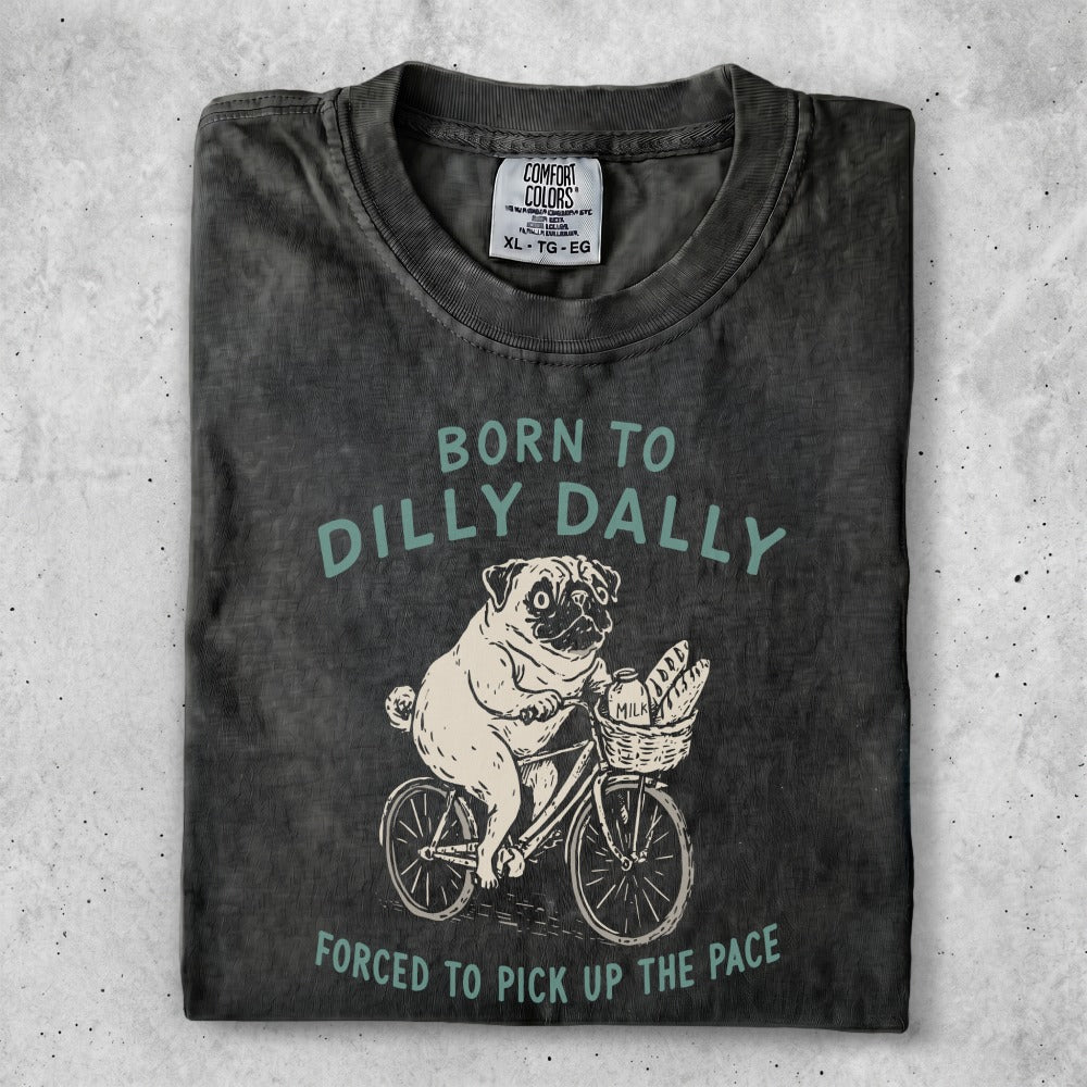 T-shirt with pug riding a bicycle and text "BORN TO DILLY DALLY FORCED TO PICK UP THE PACE."