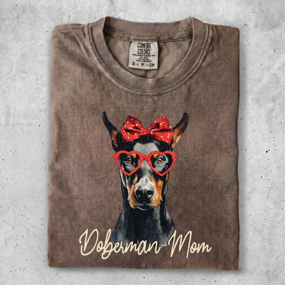 Doberman wearing heart glasses and a red bow, "Doberman Mom" text.