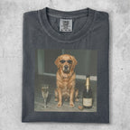 Golden retriever dog wearing sunglasses sits by a champagne bottle and glass.