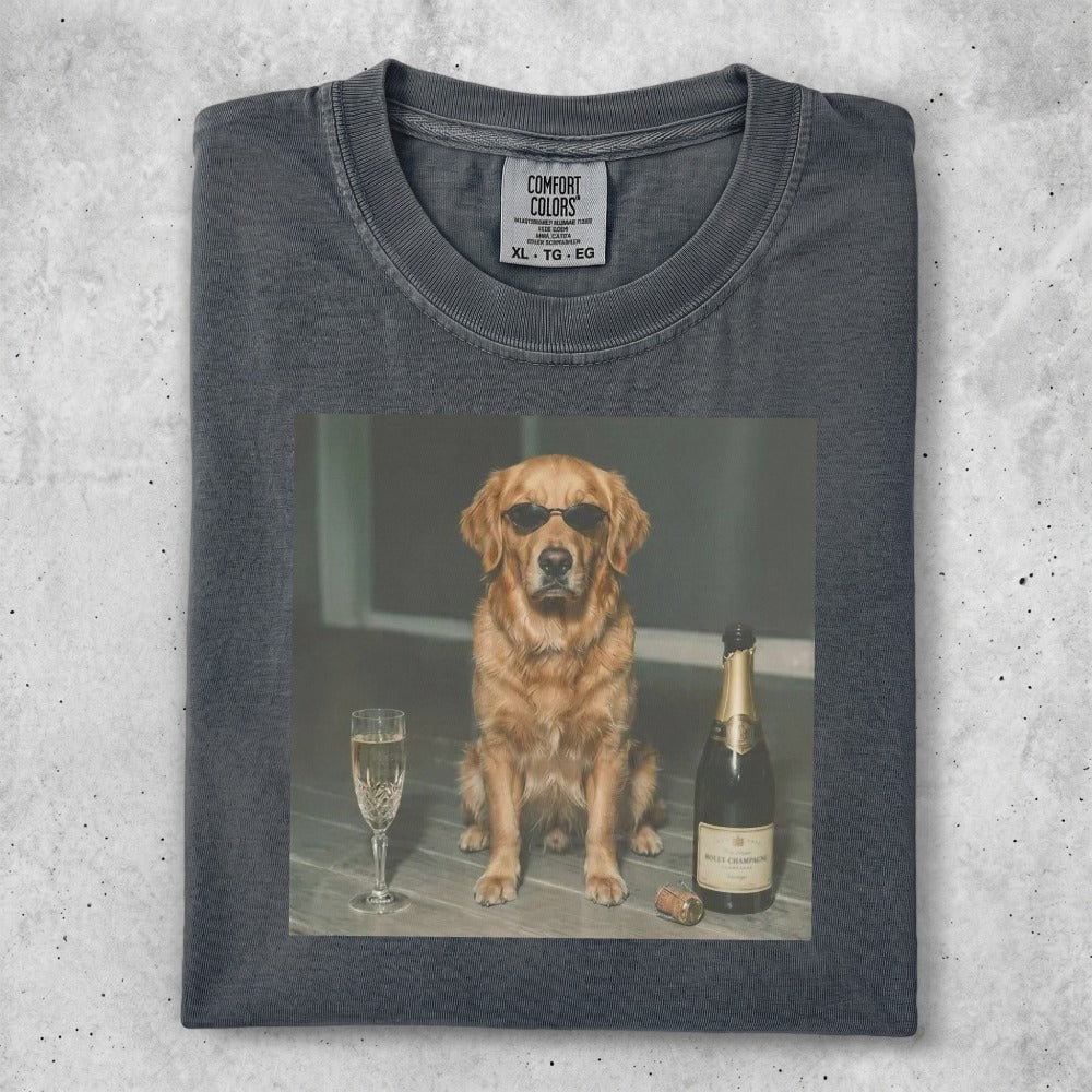 Golden retriever dog wearing sunglasses sits by a champagne bottle and glass.