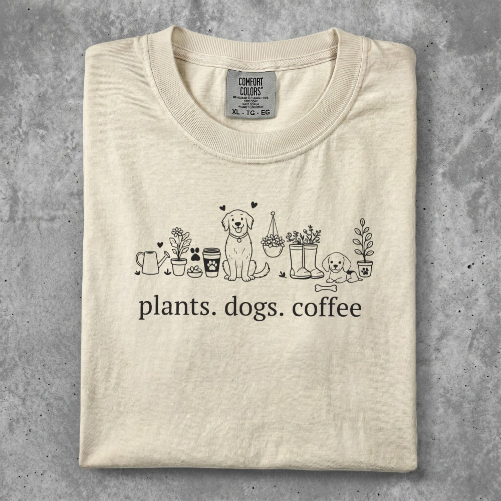 Cream t-shirt with line art of plants, dogs, and coffee cup, text reads "plants. dogs. coffee."