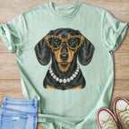 Dachshund wearing leopard glasses and diamond necklace on light green t-shirt.