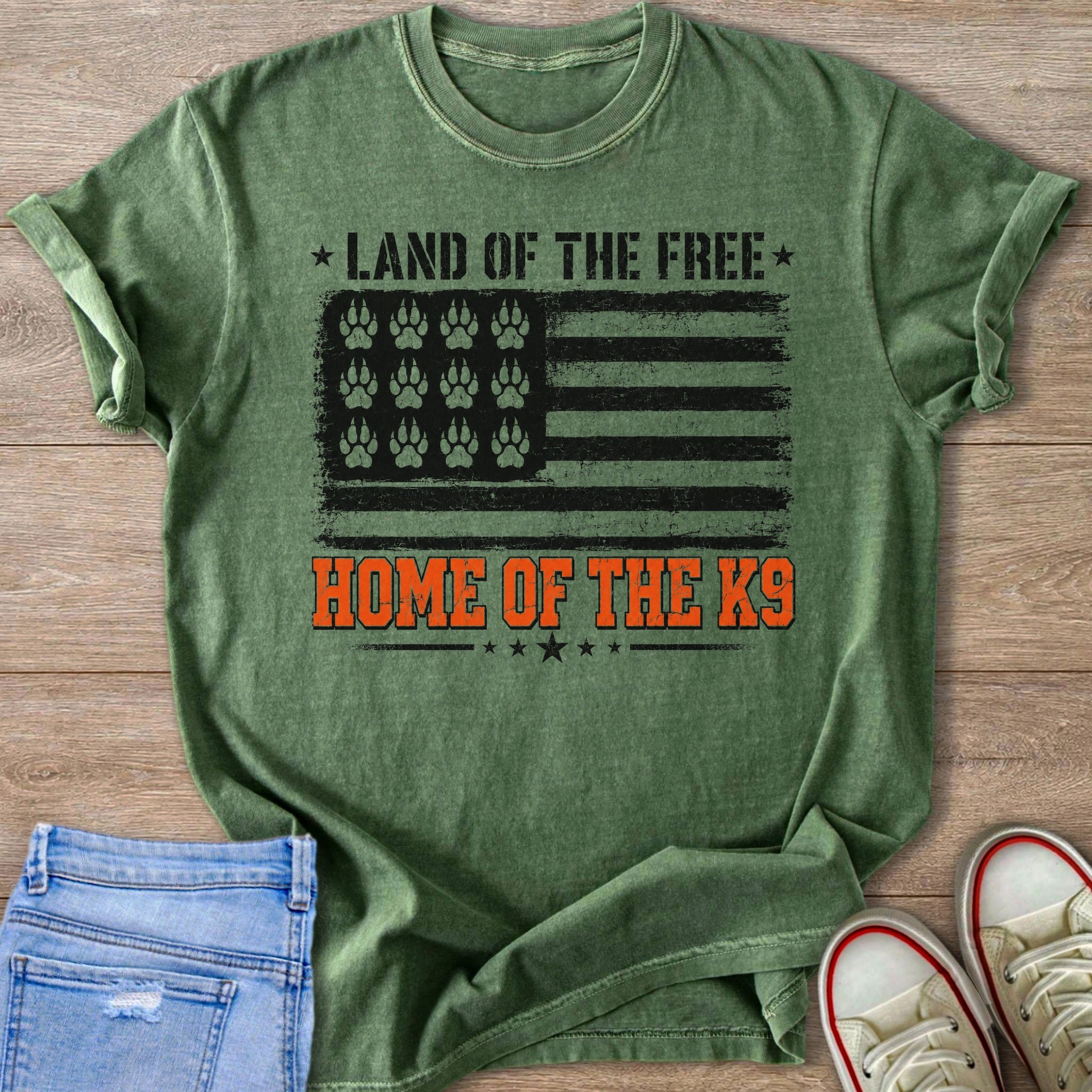 Green t-shirt with American flag graphic featuring paw prints, text "Land of the Free, Home of the K9".
