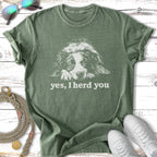 Green t-shirt with a white dog illustration and "yes, I herd you" text.
