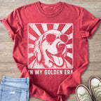 Golden Retriever dog wearing sunglasses with text "IN MY GOLDEN ERA" on shirt.