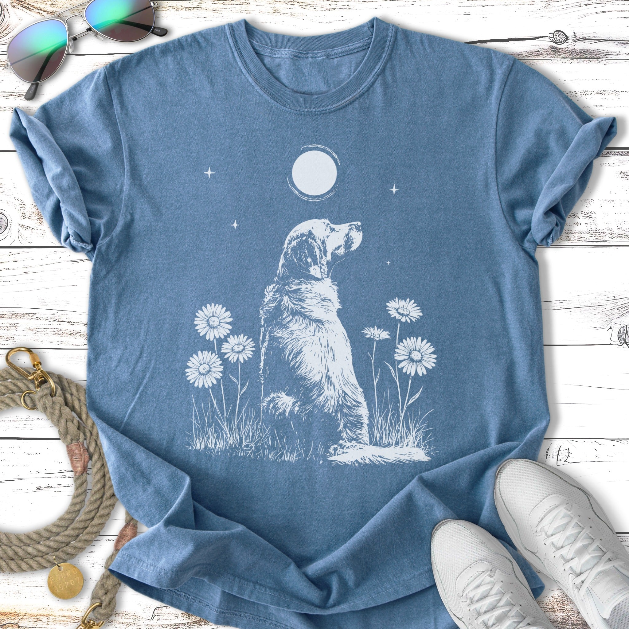 T-shirt with white drawing of a dog sitting among daisies under a moon.
