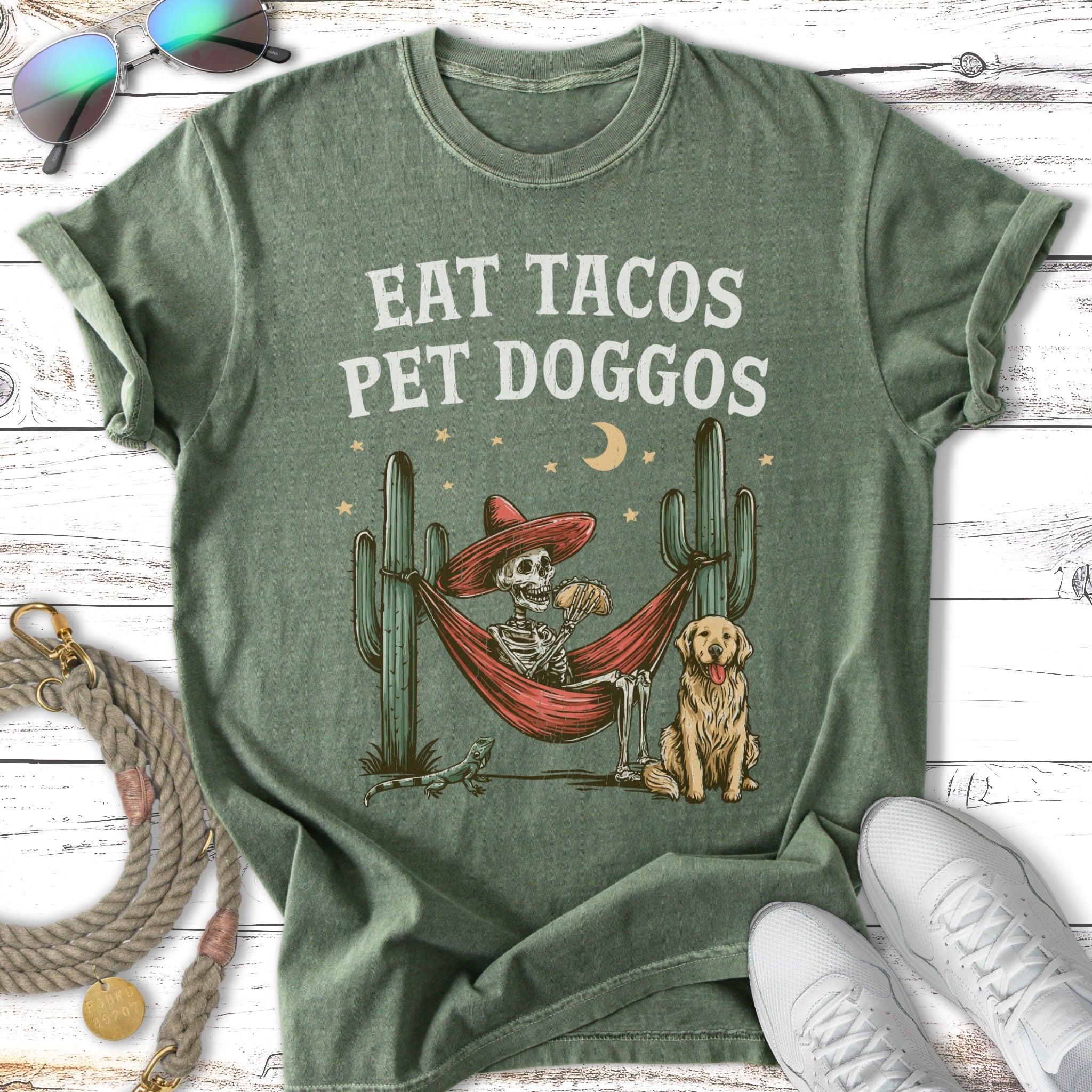 Skeleton in hammock eating tacos with doggos, cacti, and moon.