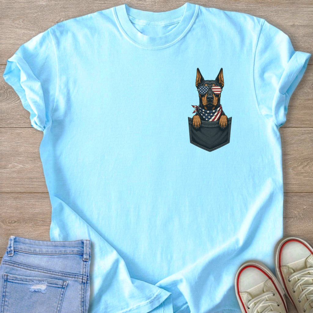Light blue t-shirt with a Doberman wearing American flag sunglasses and bandana in a pocket.