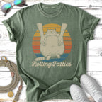 Green t-shirt with a cartoon cat being held by human hands, text "Rolling Fatties".