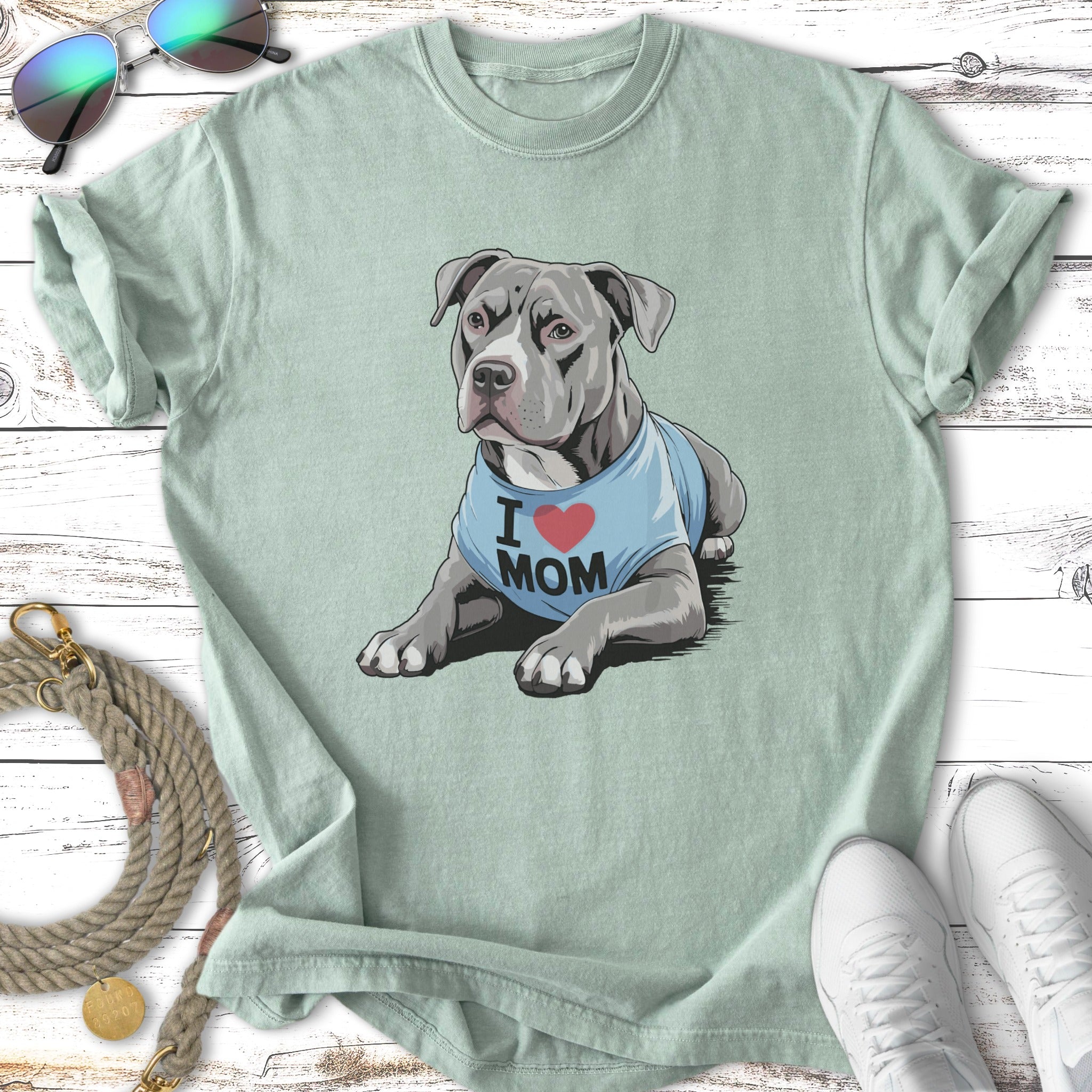 Gray pit bull wearing "I love Mom" shirt, lying down.
