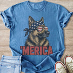 German Shepherd with American flag bandana and sunglasses on a blue shirt.