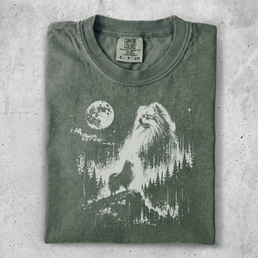 Green t-shirt with a white graphic of a wolf howling at the moon in a forest.